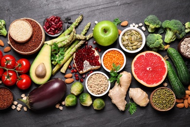 Photo of Fresh vegetables, fruits and seeds on black table, flat lay