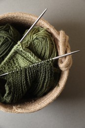 Photo of Green knitting, needles and soft yarns on light background, top view