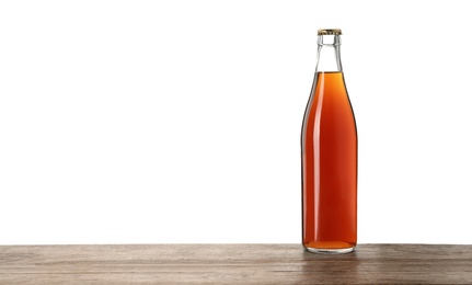 Bottle of delicious kvass on wooden table against white background