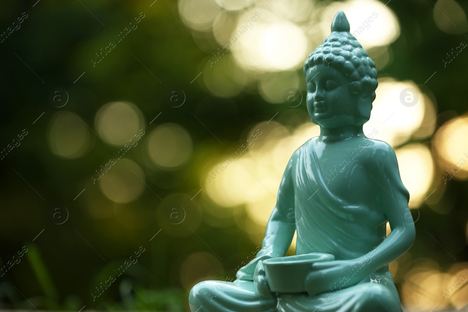 Photo of Decorative Buddha statue on blurred background outdoors. Space for text