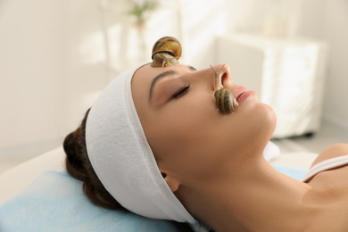 Young woman receiving snail facial massage in spa salon