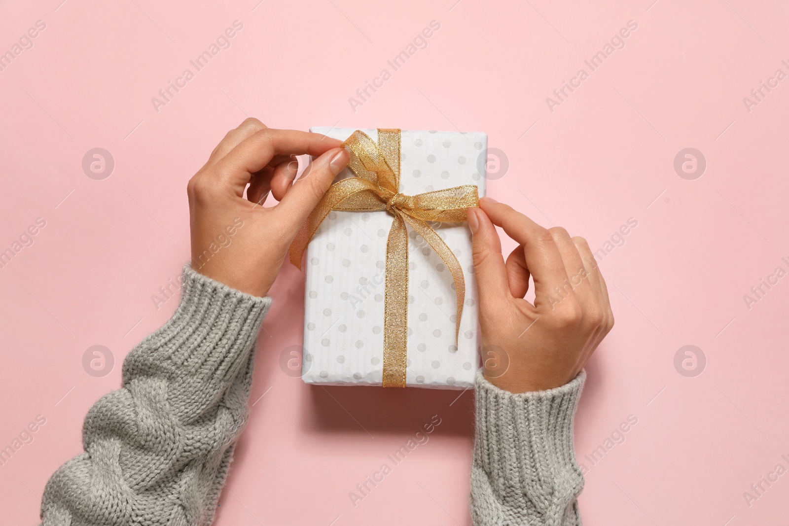 Photo of Woman with Christmas gift on pink background, top view