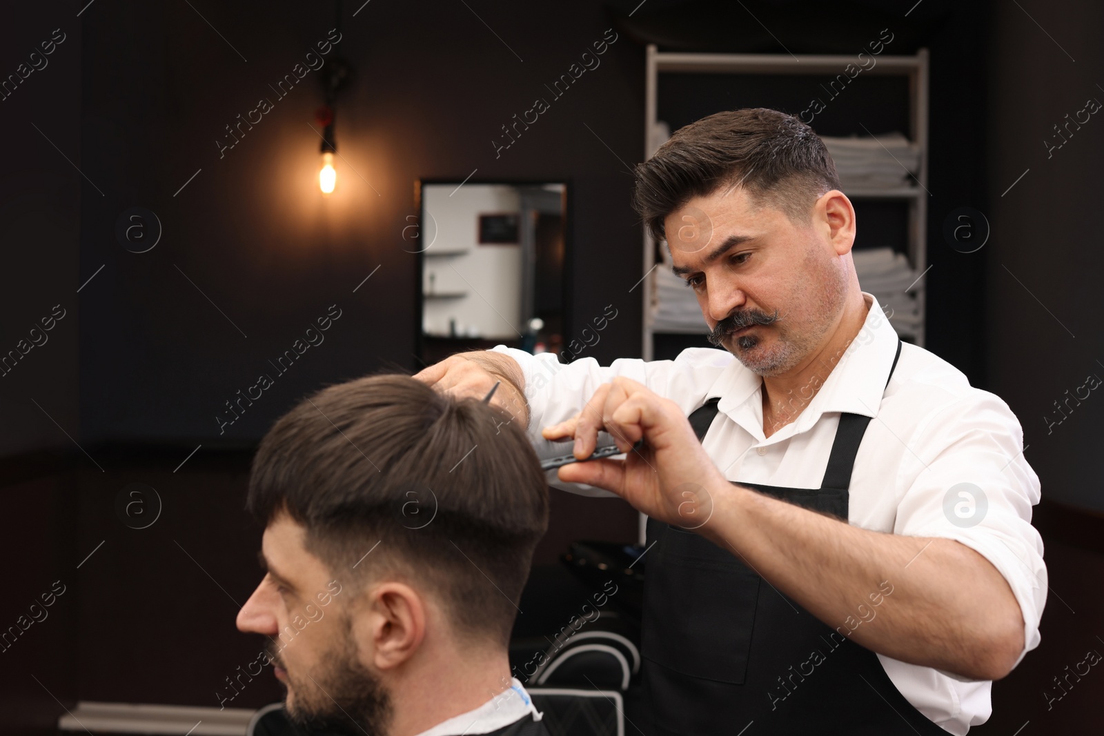 Photo of Professional hairdresser cutting man's hair in barbershop