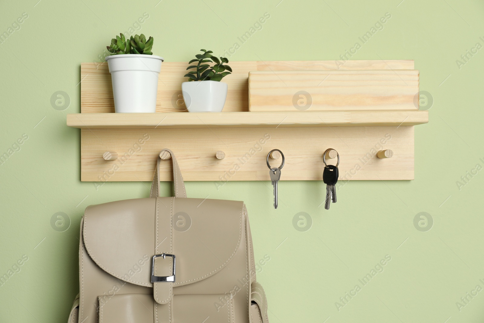 Photo of Wooden hanger for keys on light green wall