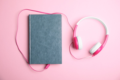 Photo of Book and modern headphones on pink background, flat lay