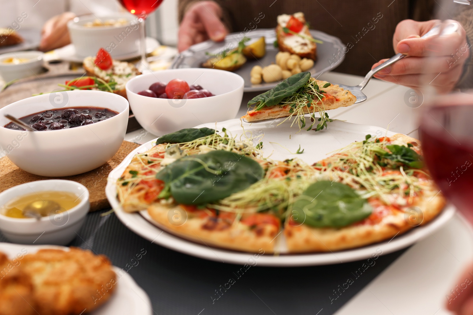 Photo of Man taking slice of pizza during brunch at table, closeup
