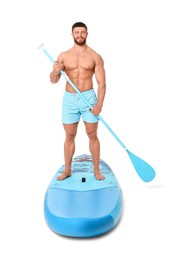 Handsome man with paddle on blue SUP board against white background