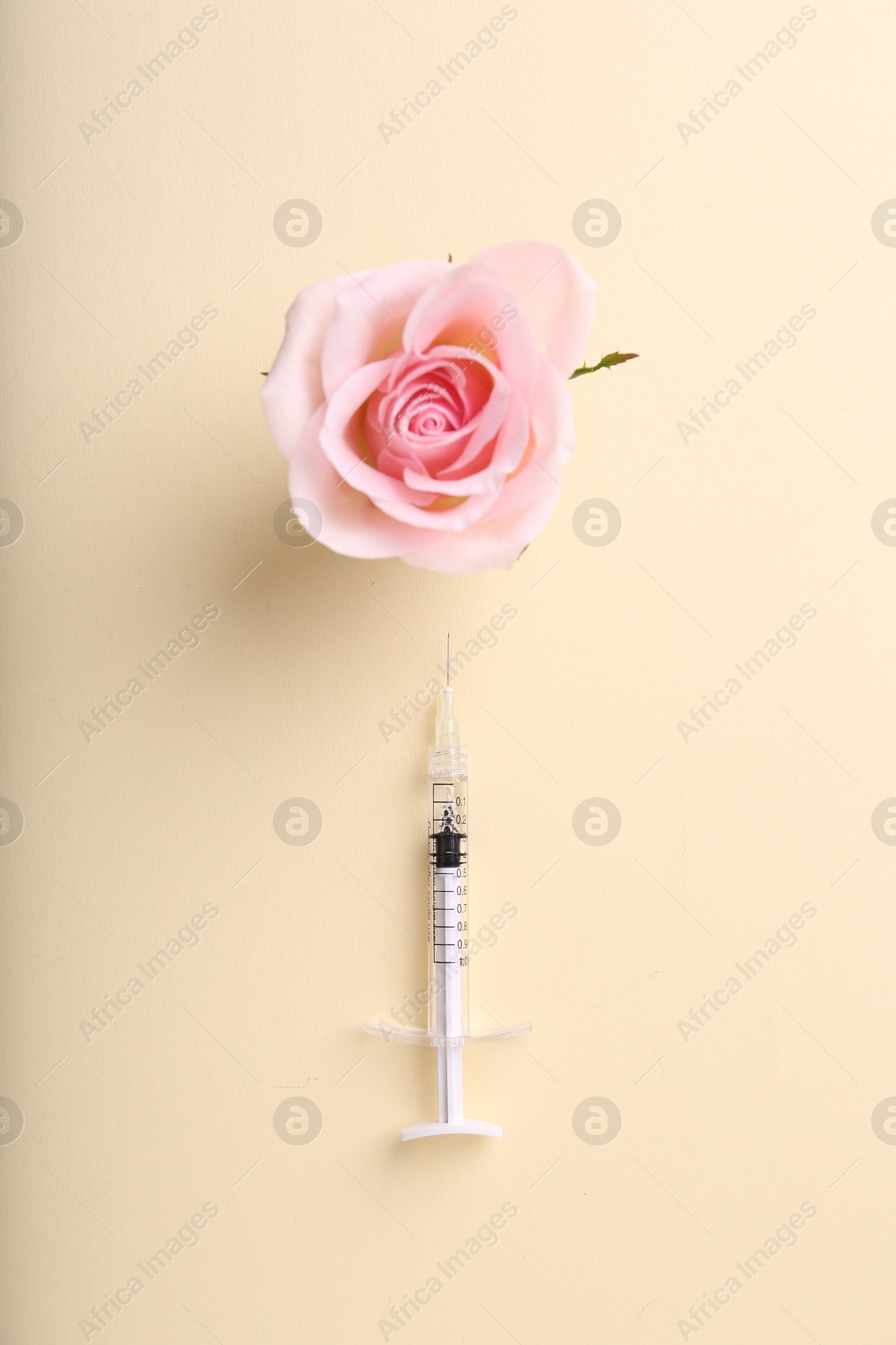 Photo of Cosmetology. Medical syringe and rose flower on yellow background, flat lay