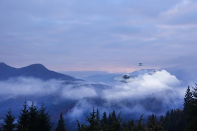 Image of Alien spaceships flying in misty mountains. UFO