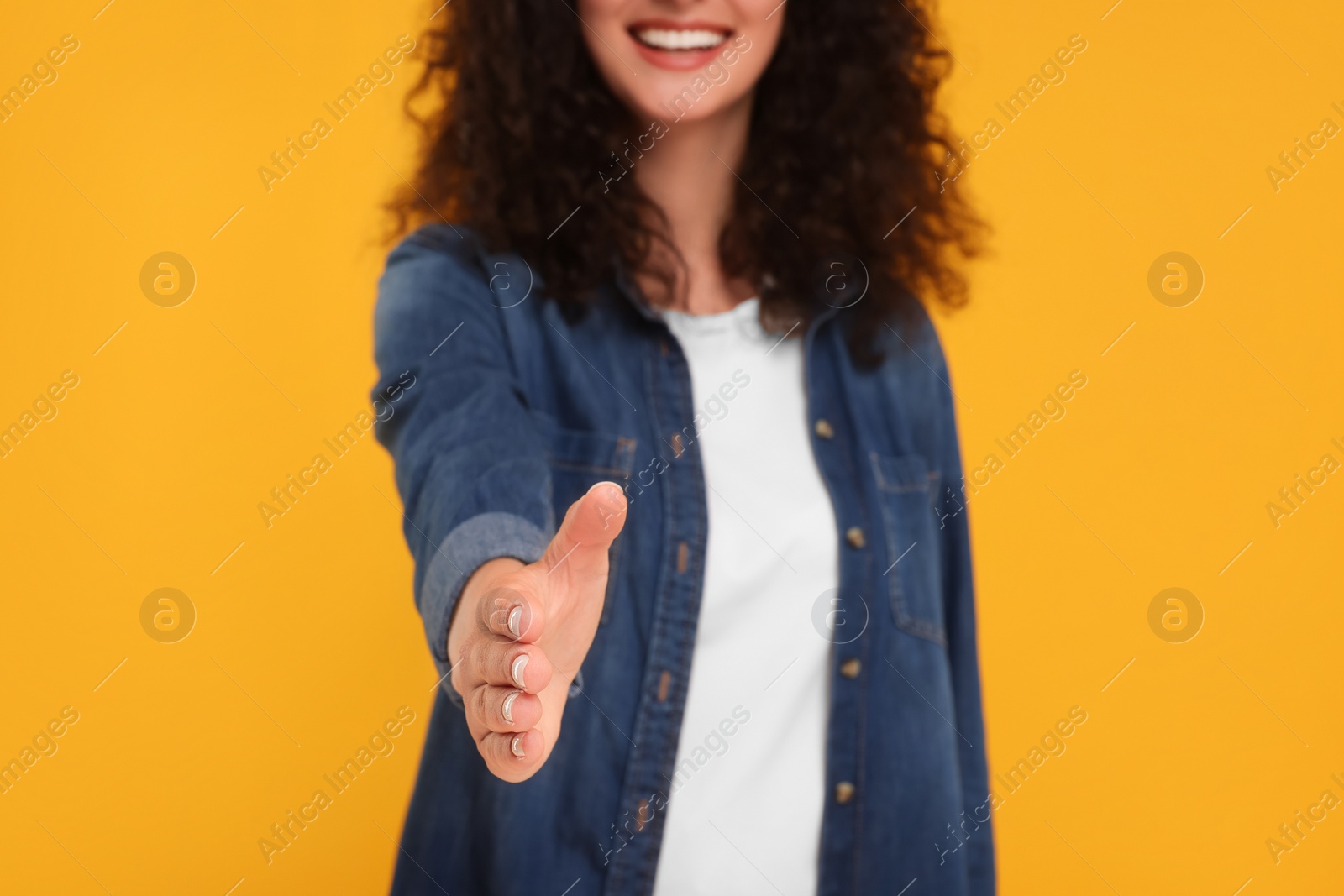 Photo of Woman welcoming and offering handshake on yellow background, closeup