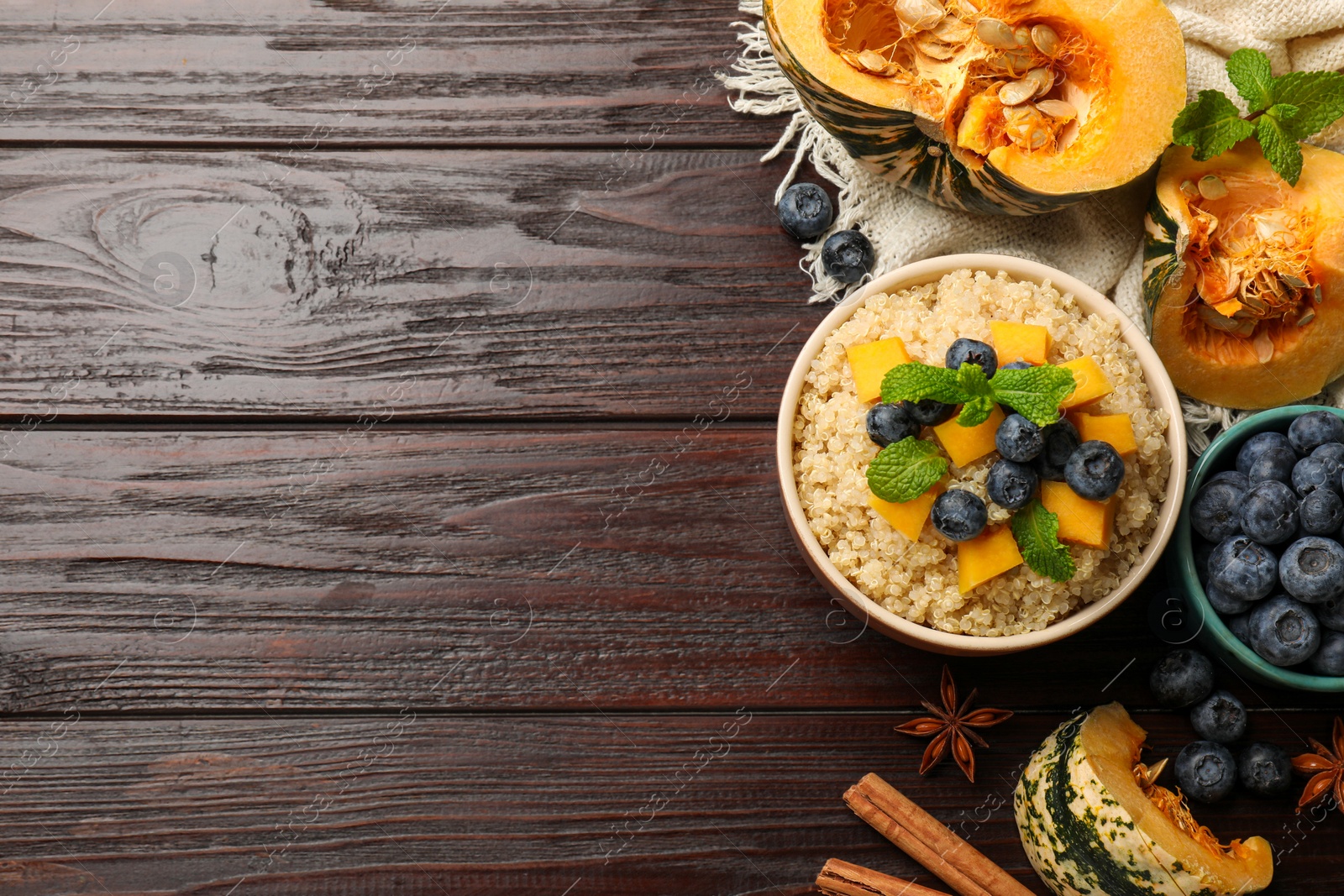 Photo of Flat lay composition with bowl of tasty quinoa porridge, pumpkin and blueberries on wooden table. Space for text