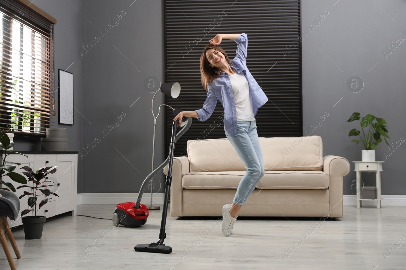 Photo of Young woman having fun while vacuuming at home