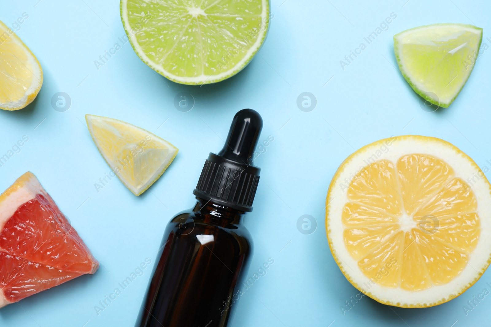 Photo of Flat lay composition with citrus essential oil on light blue background