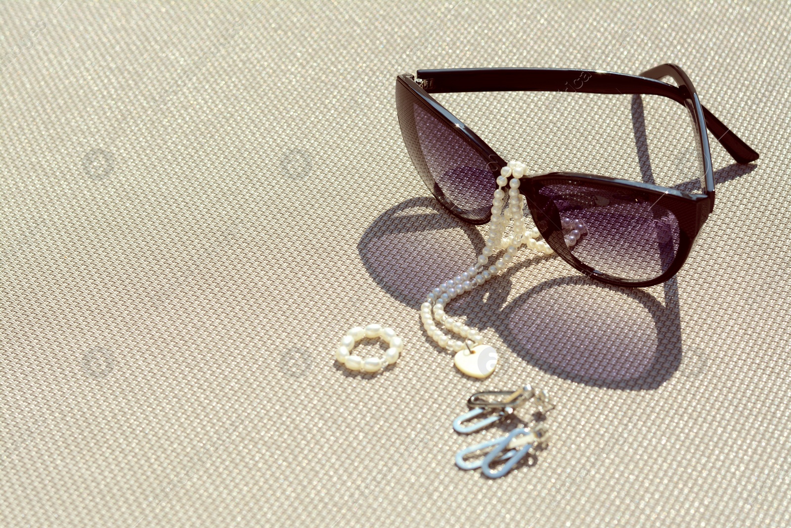 Photo of Stylish sunglasses and jewelry on grey surface, space for text