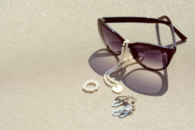Stylish sunglasses and jewelry on grey surface, space for text