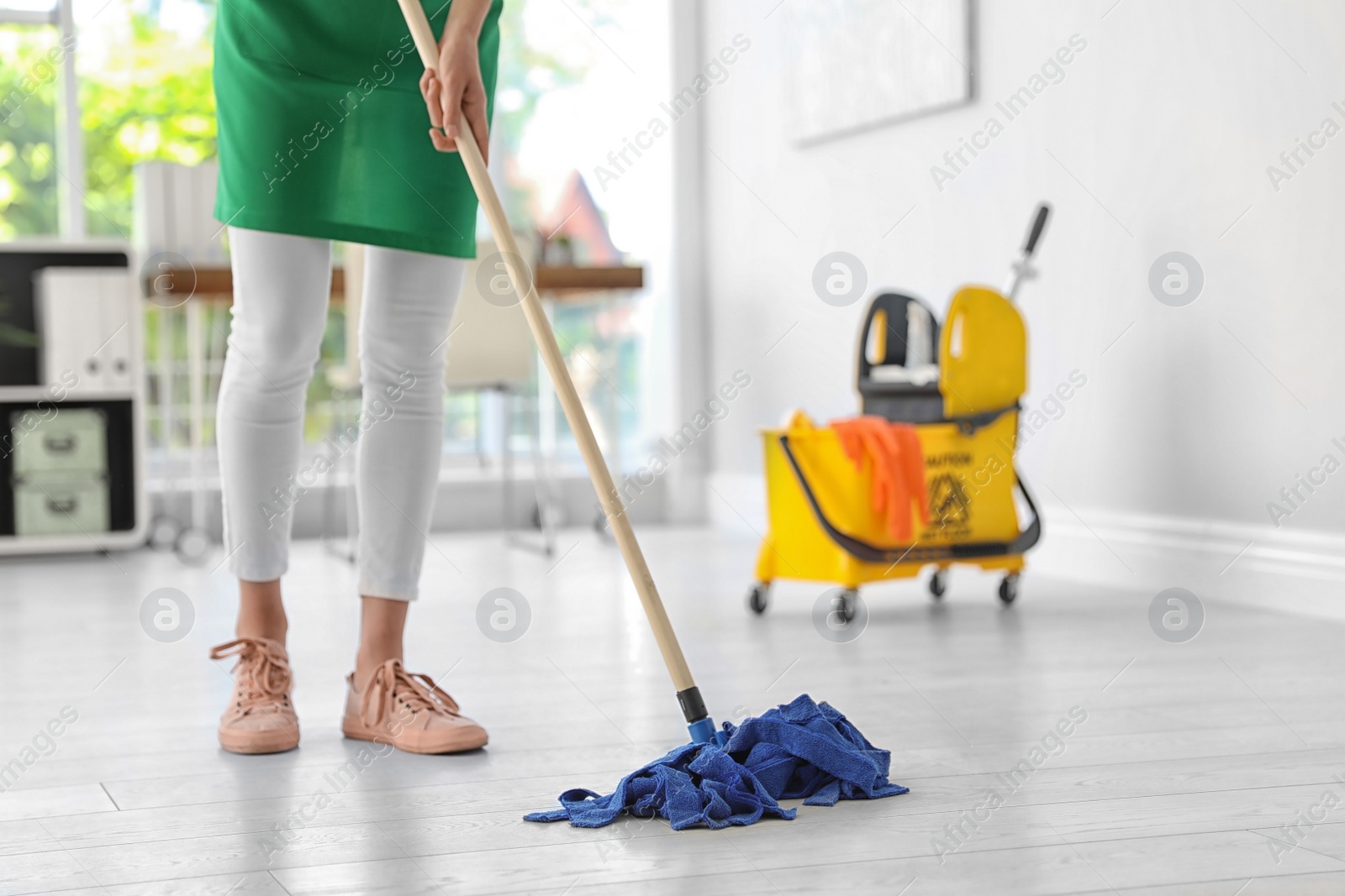 Photo of Young woman with mop cleaning floor in office