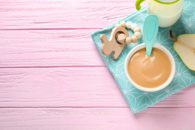 Photo of Flat lay composition with bowl of healthy baby food on pink wooden table. Space for text