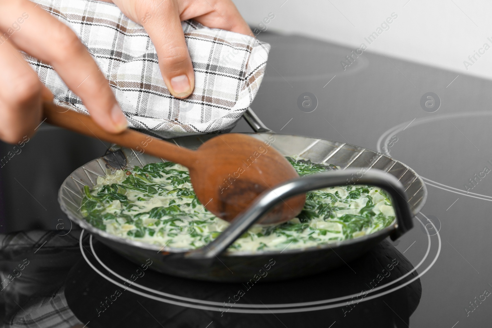 Photo of Woman cooking tasty spinach dip on kitchen stove, closeup view