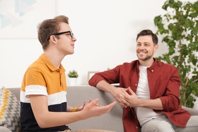 Photo of Father talking with his teenager son at home