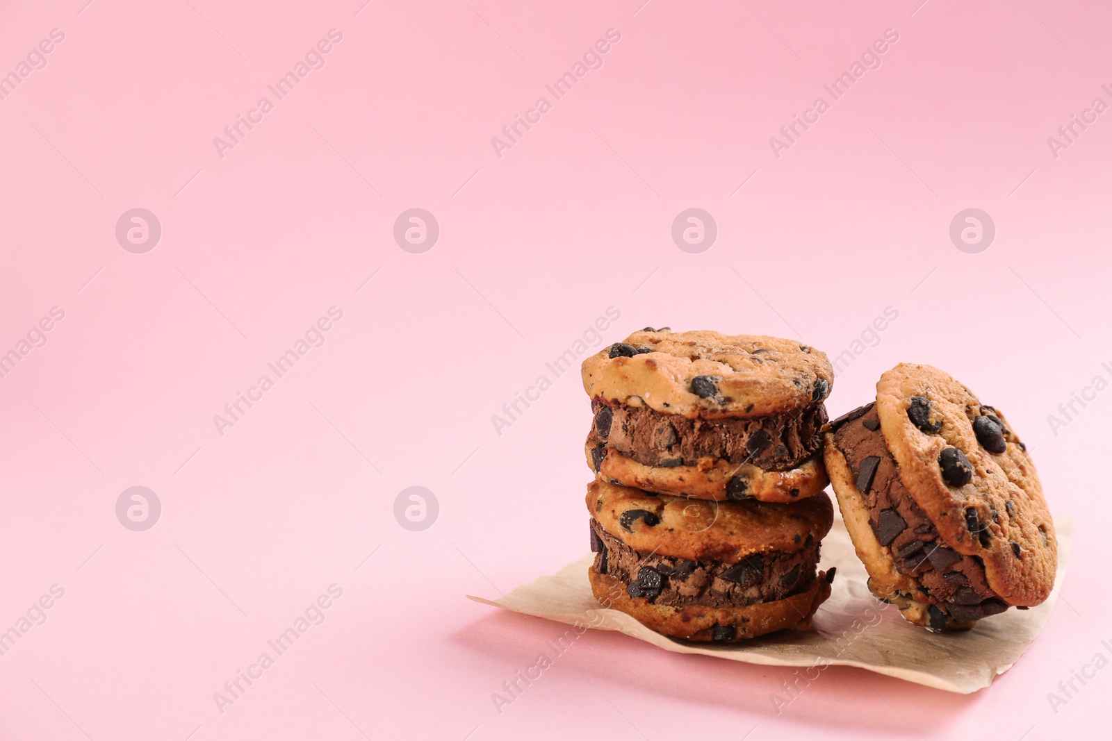 Photo of Sweet delicious ice cream cookie sandwiches on pink background. Space for text