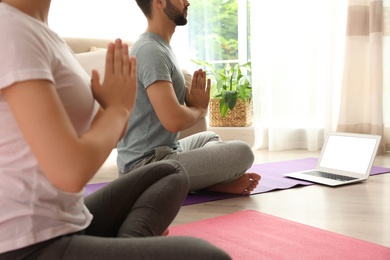 Couple practicing yoga while watching online class at home during coronavirus pandemic, closeup. Social distancing