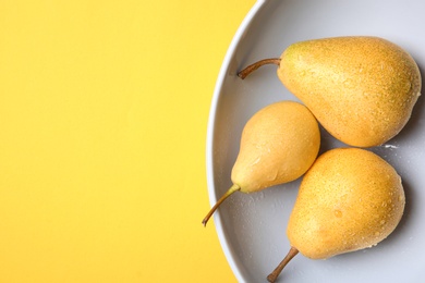 Plate with ripe pears on color background, top view. Space for text