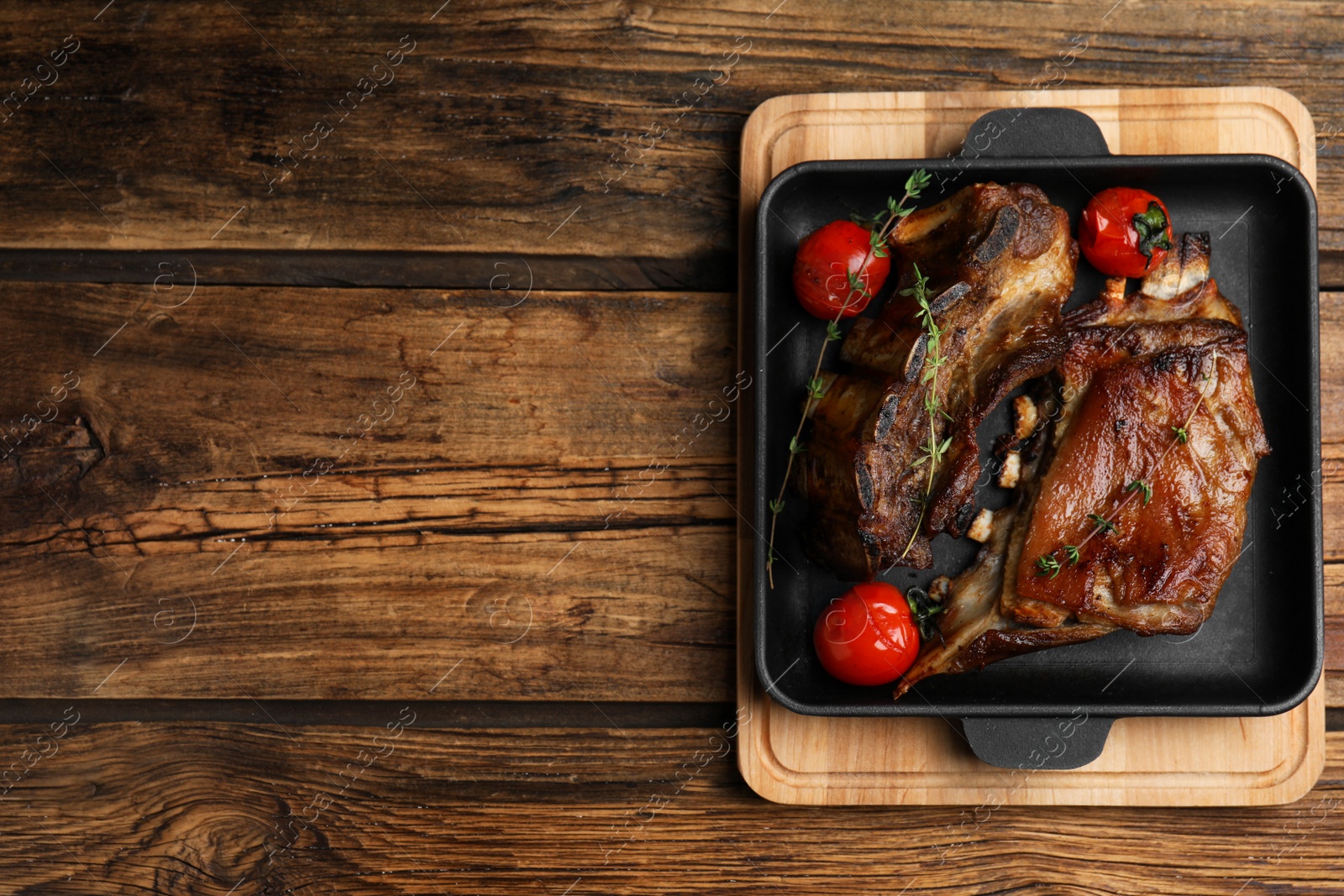 Photo of Delicious roasted ribs served on wooden table, top view. Space for text