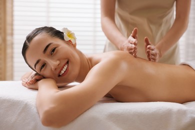 Woman receiving back massage on couch in spa salon