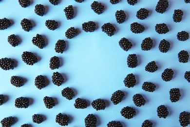 Flat lay composition with ripe blackberries on blue background. Space for text