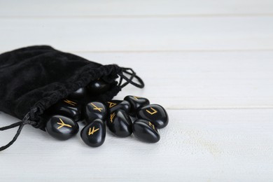 Bag with black rune stones on white wooden table