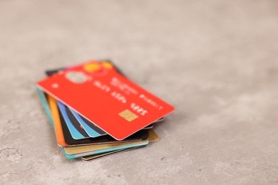 Photo of Pile of different credit cards on grey table, closeup. Space for text