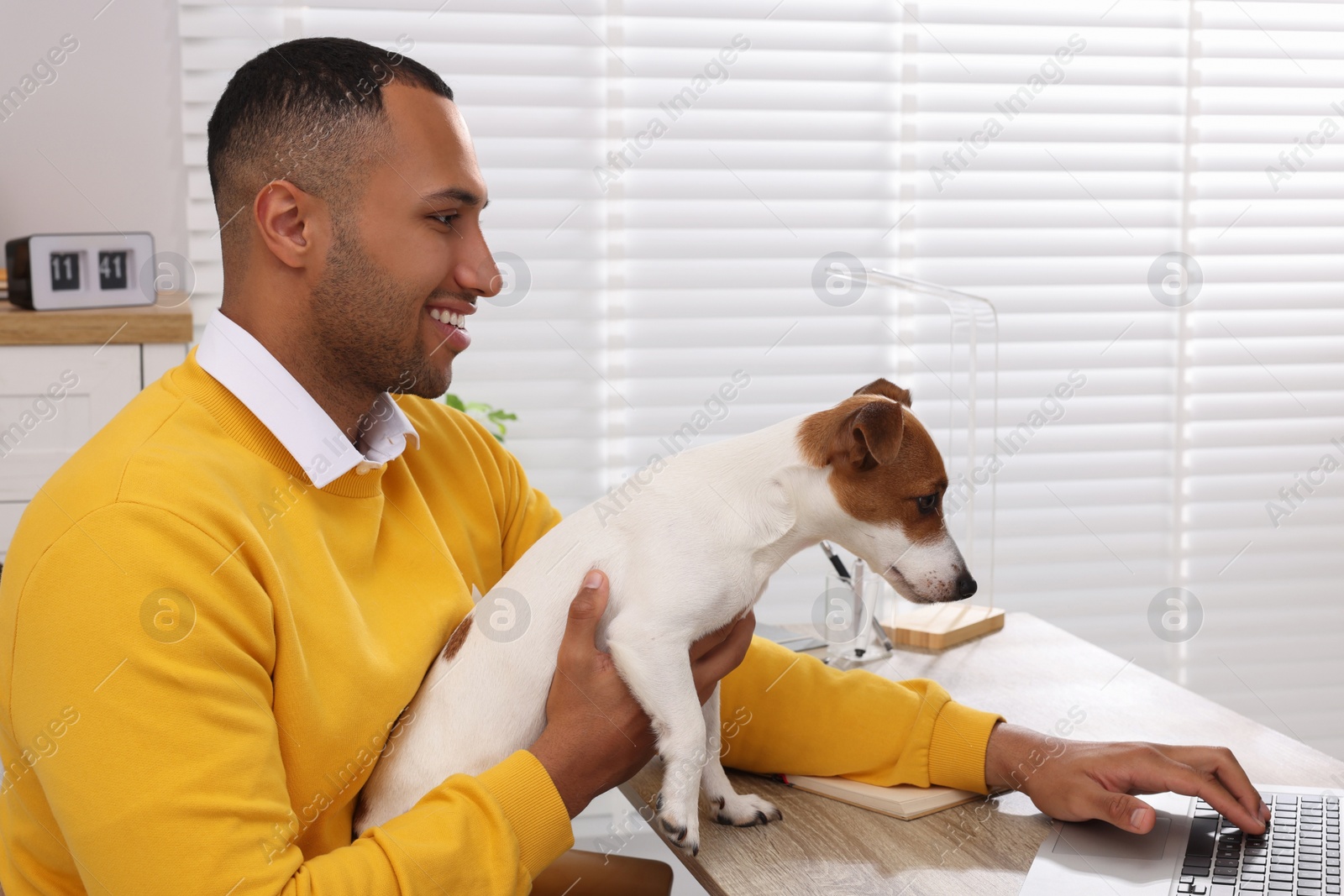 Photo of Young man with Jack Russell Terrier working at desk in home office