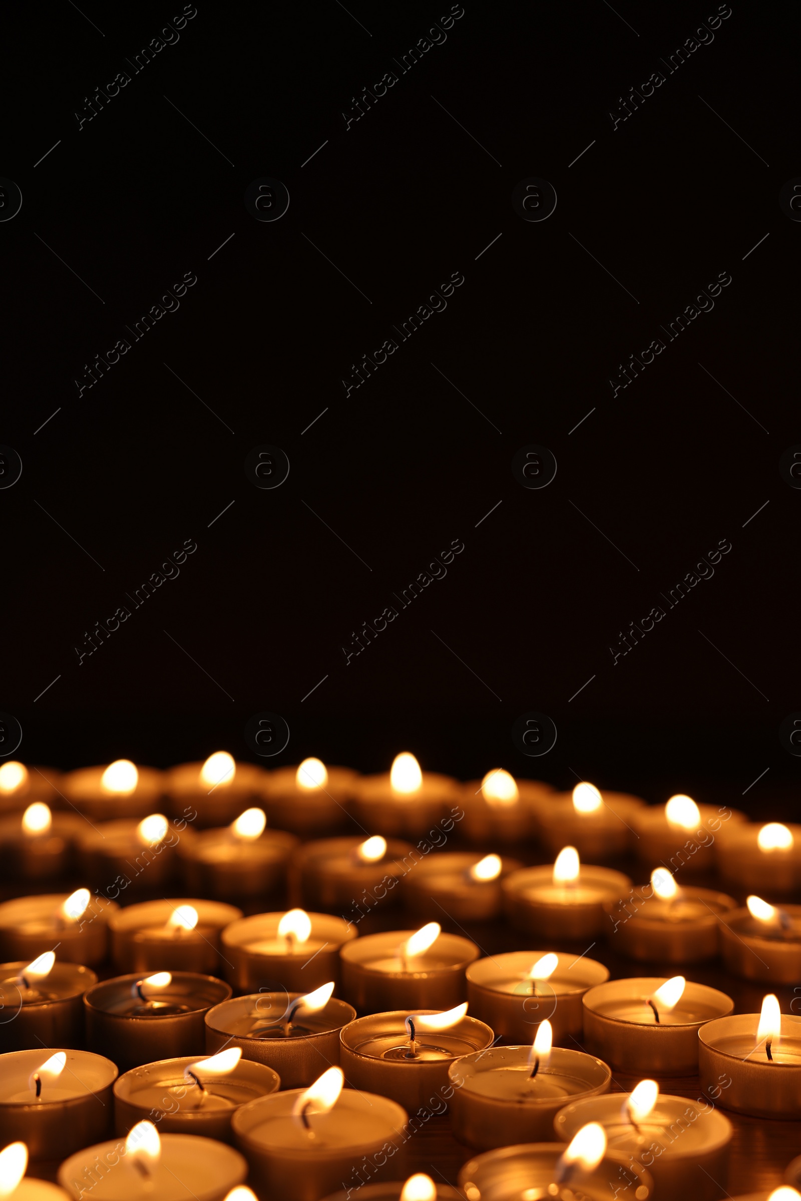 Photo of Burning candles on table against black background, space for text