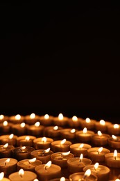 Burning candles on table against black background, space for text