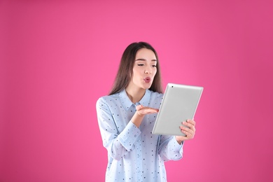 Woman using tablet for video chat on color background