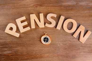 Photo of Word "PENSION" made of letters and compass on wooden background