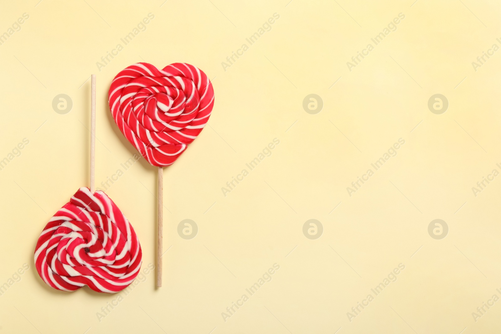 Photo of Sweet heart shaped lollipops on beige background, flat lay with space for text. Valentine's day celebration