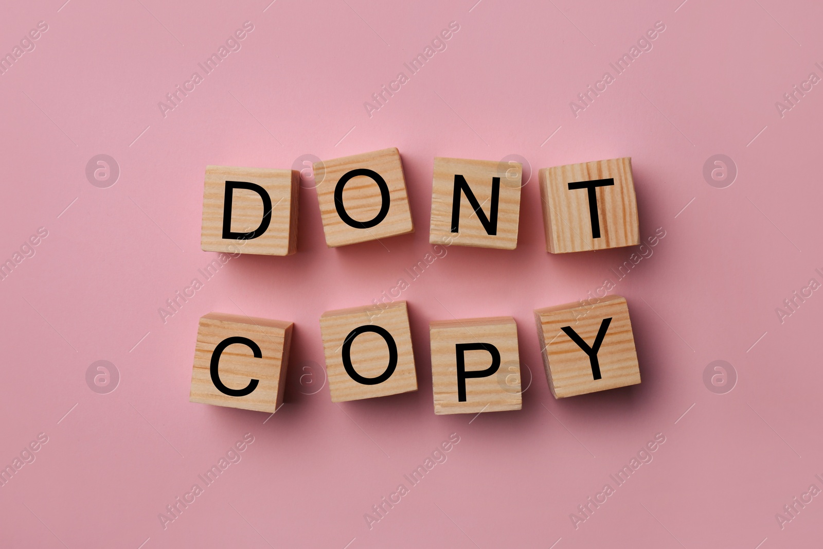 Photo of Wooden cubes with words Don't Copy on pink background, flat lay. Plagiarism concept