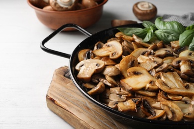 Delicious cooked mushrooms in frying pan on table. Space for text