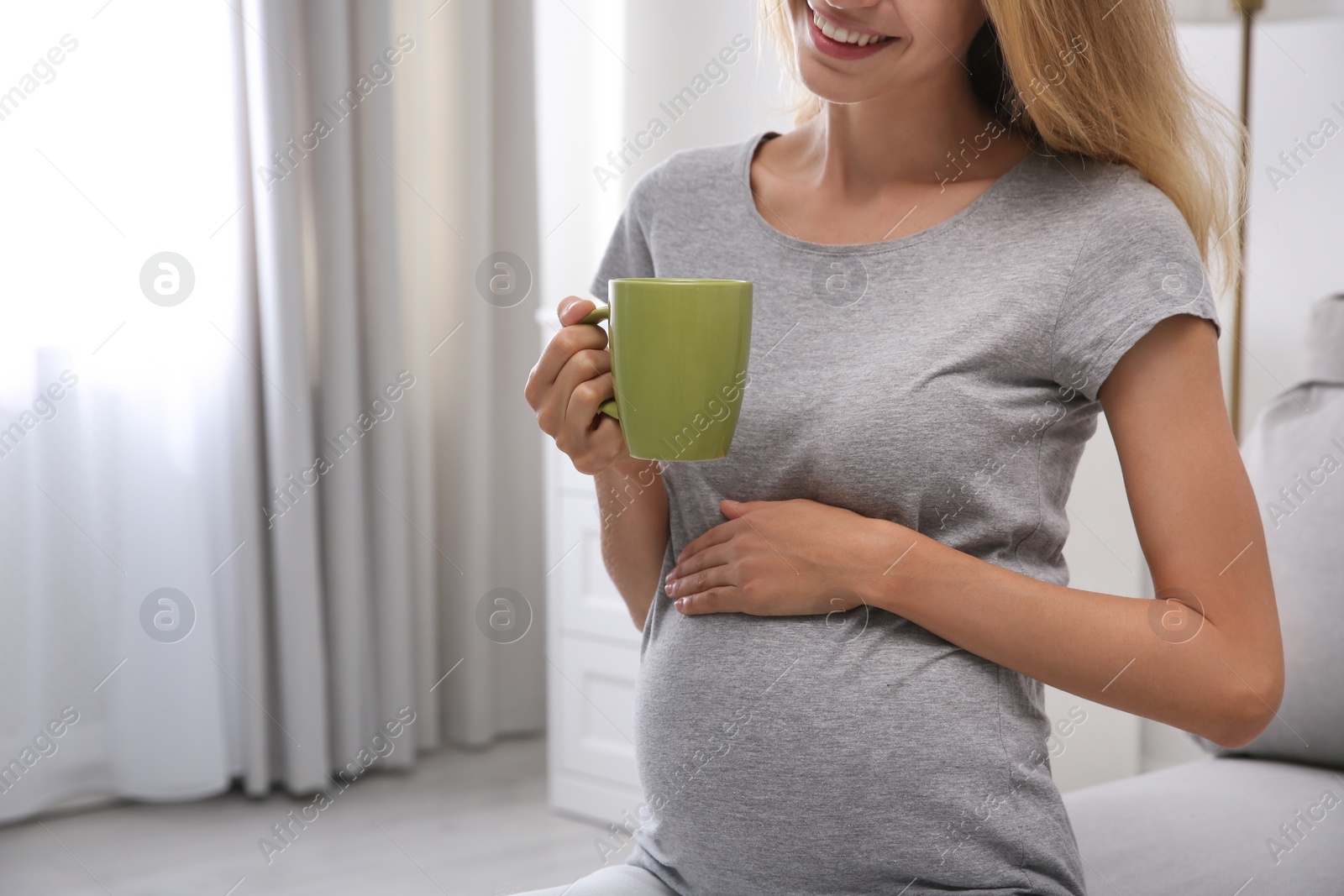 Photo of Beautiful pregnant woman drinking tea at home, closeup