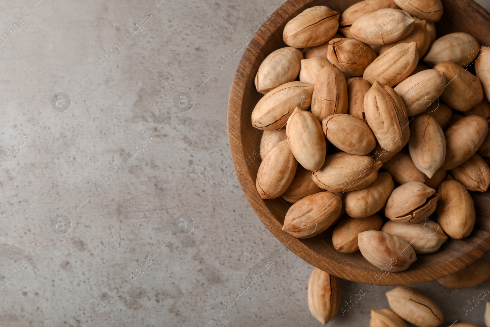 Photo of Pecan nuts in bowl and space for text on gray background, top view