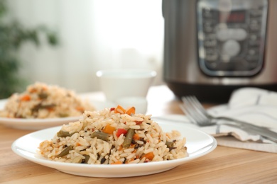 Photo of Delicious rice with vegetables on wooden table, closeup. Multi cooker recipes