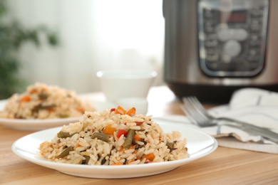 Delicious rice with vegetables on wooden table, closeup. Multi cooker recipes