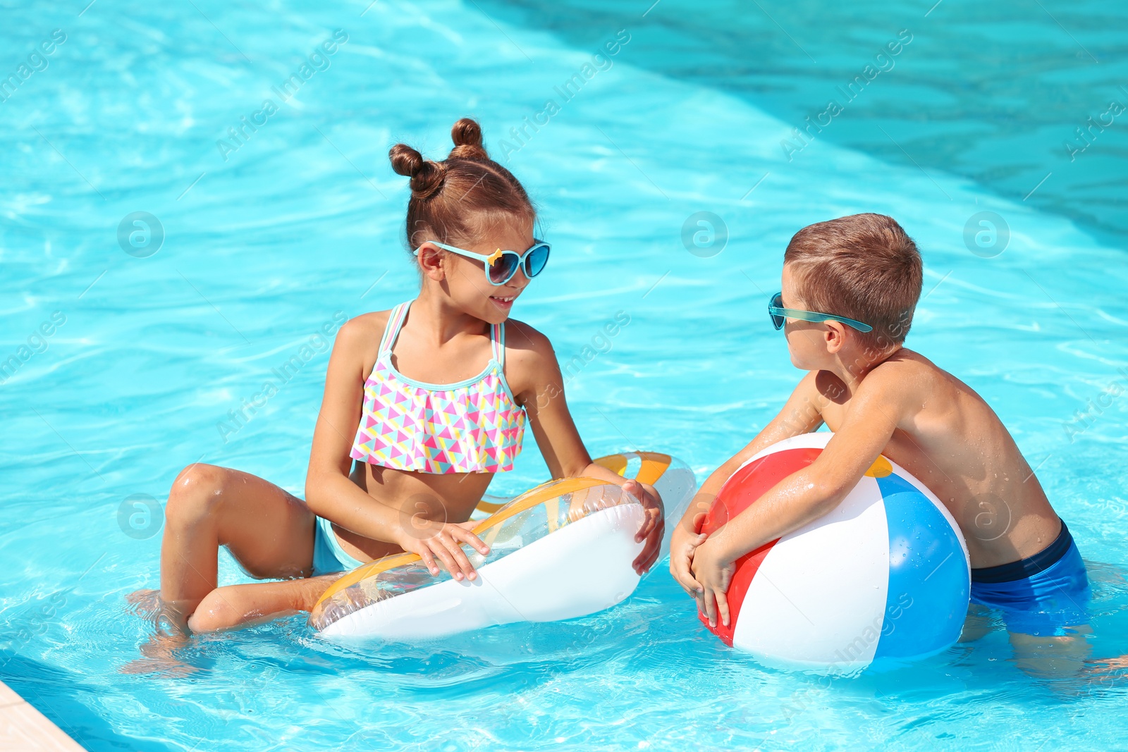 Photo of Cute little children with inflatable toys in swimming pool