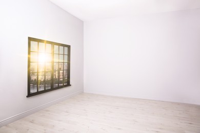 Spacious sunlit room with white walls and wooden floor
