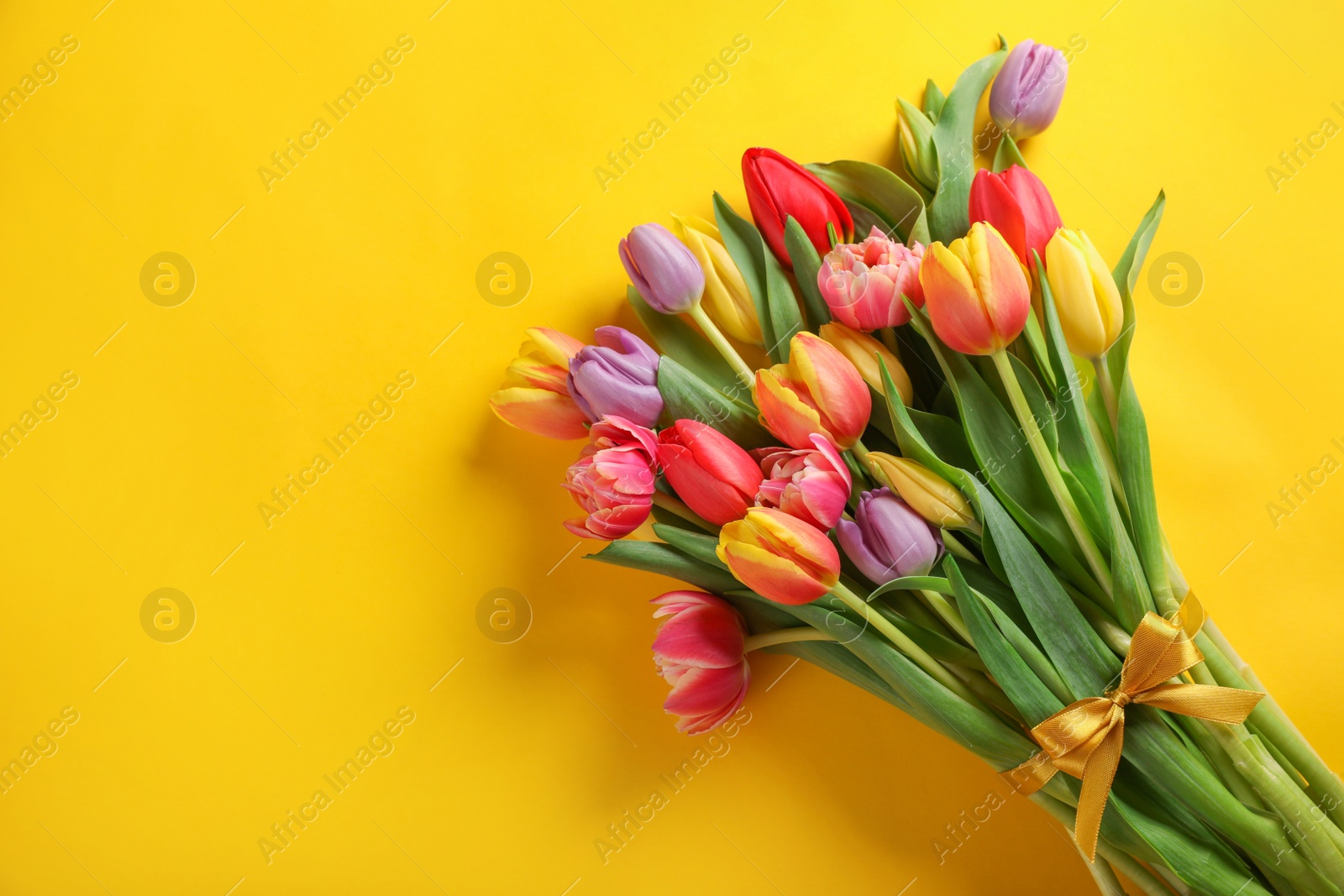 Photo of Bunch of beautiful tulips on yellow background, top view. Space for text