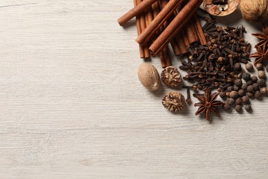 Photo of Different spices and nuts on wooden table, flat lay. Space for text