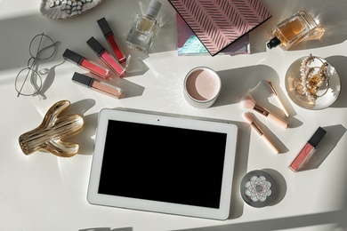 Photo of Flat lay composition with tablet and cosmetic accessories on light background, space for design. Blogger's workplace