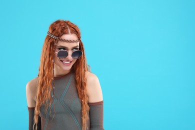 Photo of Stylish young hippie woman in sunglasses on light blue background, space for text