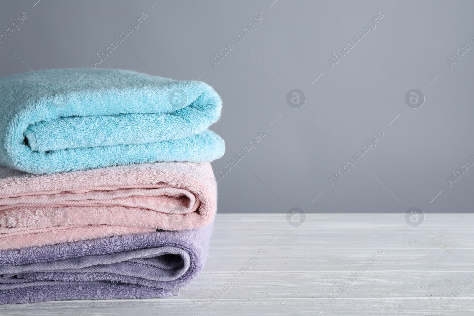 Photo of Fresh towels on wooden table, space for text